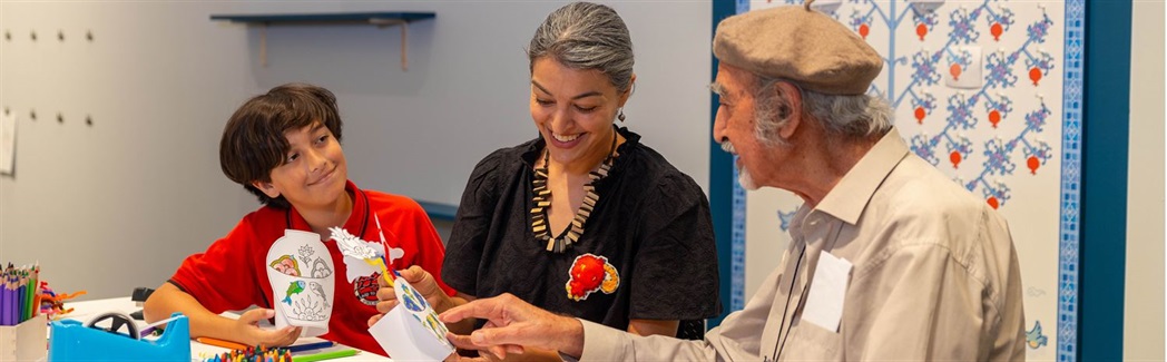 Three people creating a paper flower vase together in the Know My Name making space at RMOA.